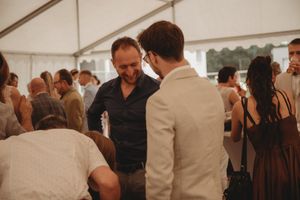 Guests mingling and chatting at a social gathering under a tent.