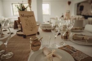 Elegant wedding table setting with rustic brown paper decor, wine glasses and white plates on a textured tablecloth.