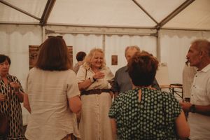 Group of guests socializing at an indoor event under a white tent.