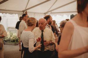 Guests mingle and dance under a white tent at an elegant wedding reception celebration.