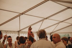 Wedding reception guests gathering under a white tent canopy during a celebration.