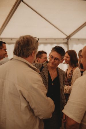 Group of guests engaged in conversation during an indoor wedding reception.
