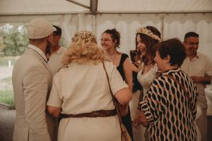 Group of wedding guests sharing laughs and conversation at an outdoor reception.