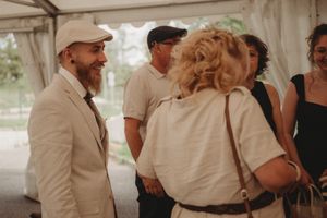 Guests mingle and chat during a casual social gathering under a white tent.