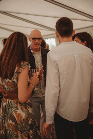 Small group engaged in conversation under a white event tent.