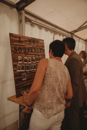 Guests viewing wooden souvenir photo display board at wedding reception.