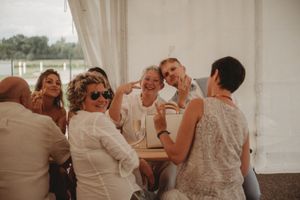 A lively group enjoying drinks and conversation under a white tent at a wedding reception.
