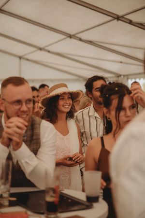 Guests enjoying a celebration under white tent at outdoor event.
