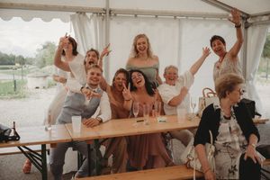 Wedding party celebrating with energy and enthusiasm under white tent reception.