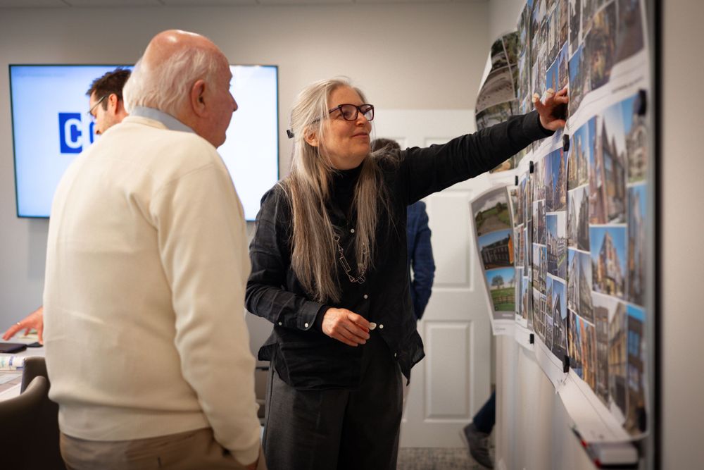 Team members examining project photos on wall during office meeting.