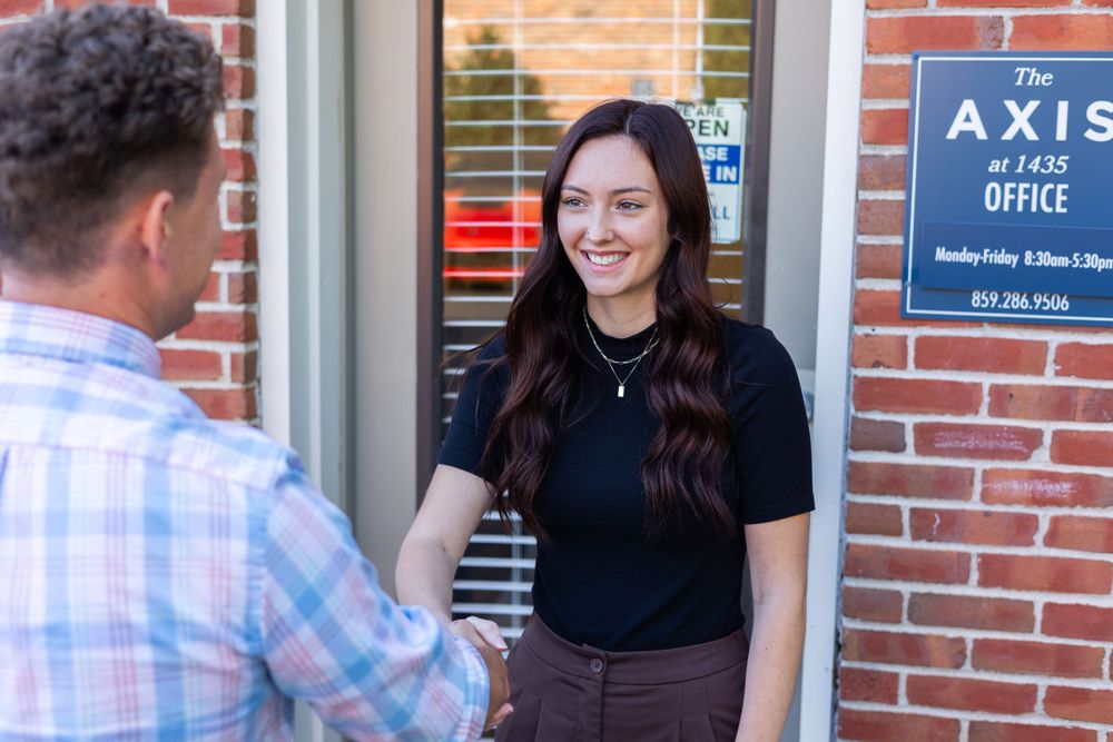 Professional greeting at entrance of Axis office building with brick exterior.