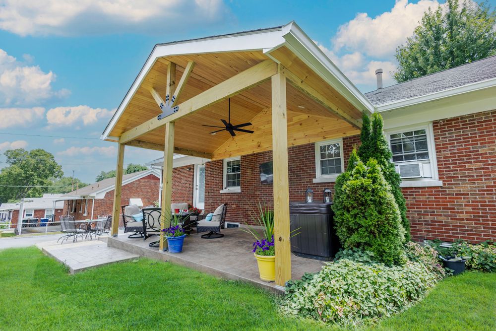 Covered brick patio with wooden beams and ceiling fans creating a cozy outdoor living space.