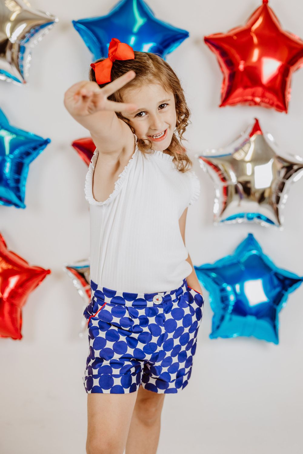 Playful pose in patriotic outfit with metallic star balloon backdrop.