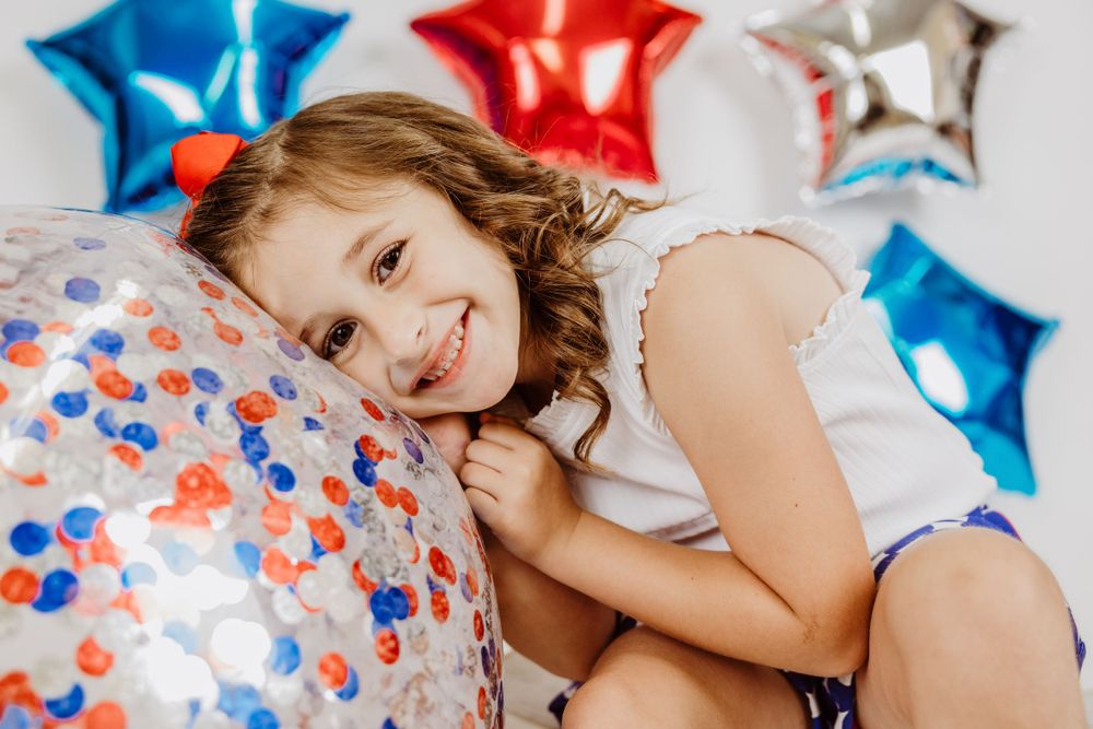 Festive scene with metallic star balloons in red, blue and silver colors arranged against white.
