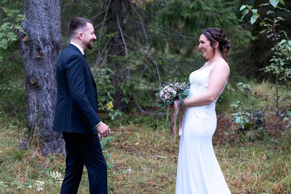 Bride and groom share a moment in a wooded forest setting with natural lighting.
