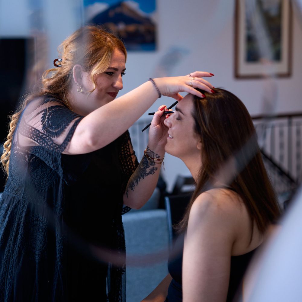 Professional makeup artist applying cosmetics in a bright indoor setting.