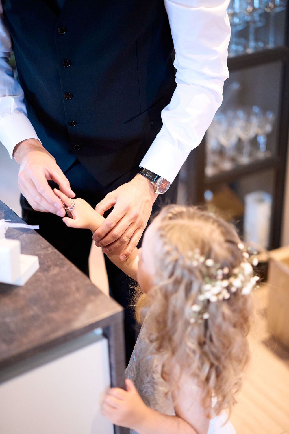 Close-up of hands adjusting a delicate hair accessory on curly blonde hair.