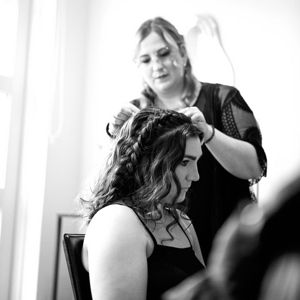 A hairstylist working on creating an elegant updo in black and white photography.