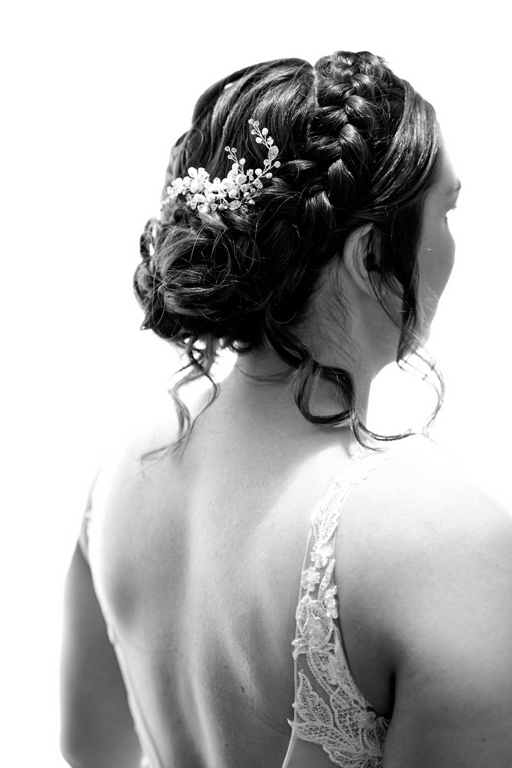 Black and white portrait showing intricate braided updo with floral hair accessories.