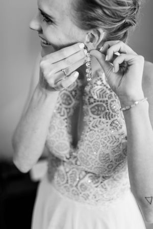Close-up of a lace wedding dress detail and crystal dangle earring.