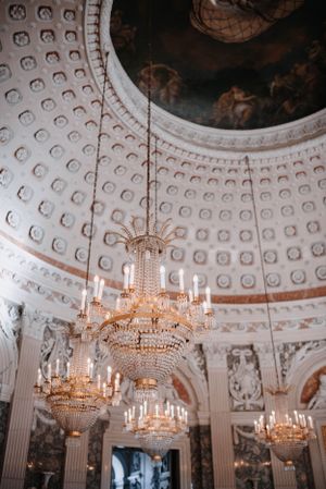 Ornate domed ceiling with crystal chandeliers in elegant historic ballroom.
