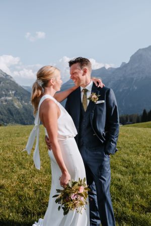 A wedding couple shares an intimate moment against a backdrop of stunning mountain scenery.