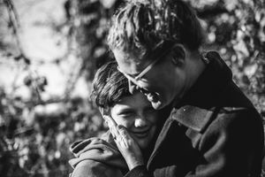 BW image of a mother holding her son's face and smiling at him.
