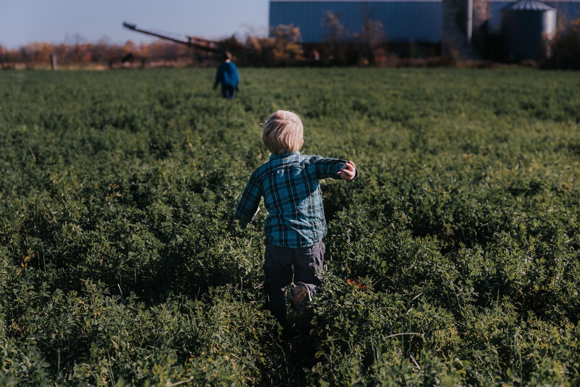 A child runs with arms spread through a clean field.