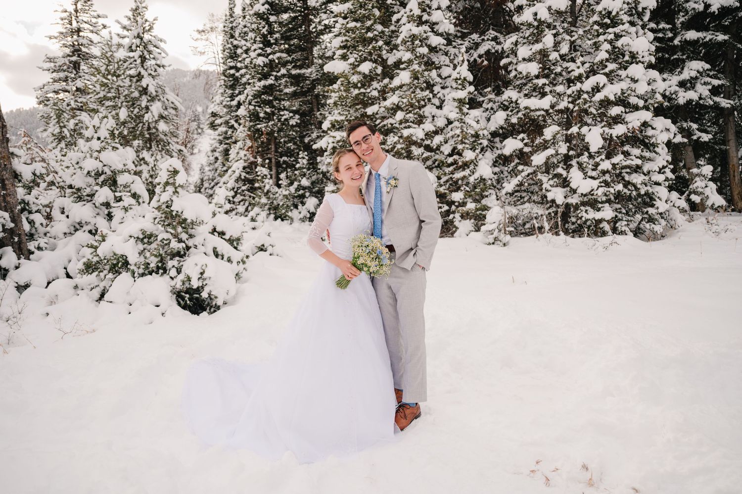 A bride and groom share an intimate moment in a snowy winter forest setting.