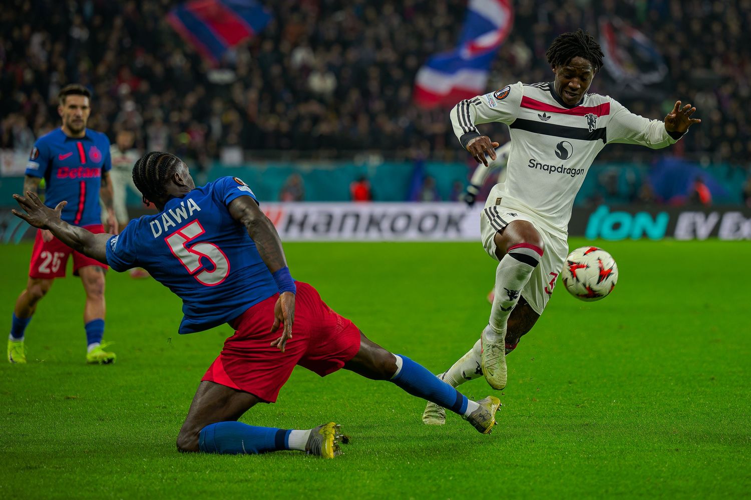 Soccer players in action during an intense match between Crystal Palace and Besiktas with a sliding tackle attempt.
