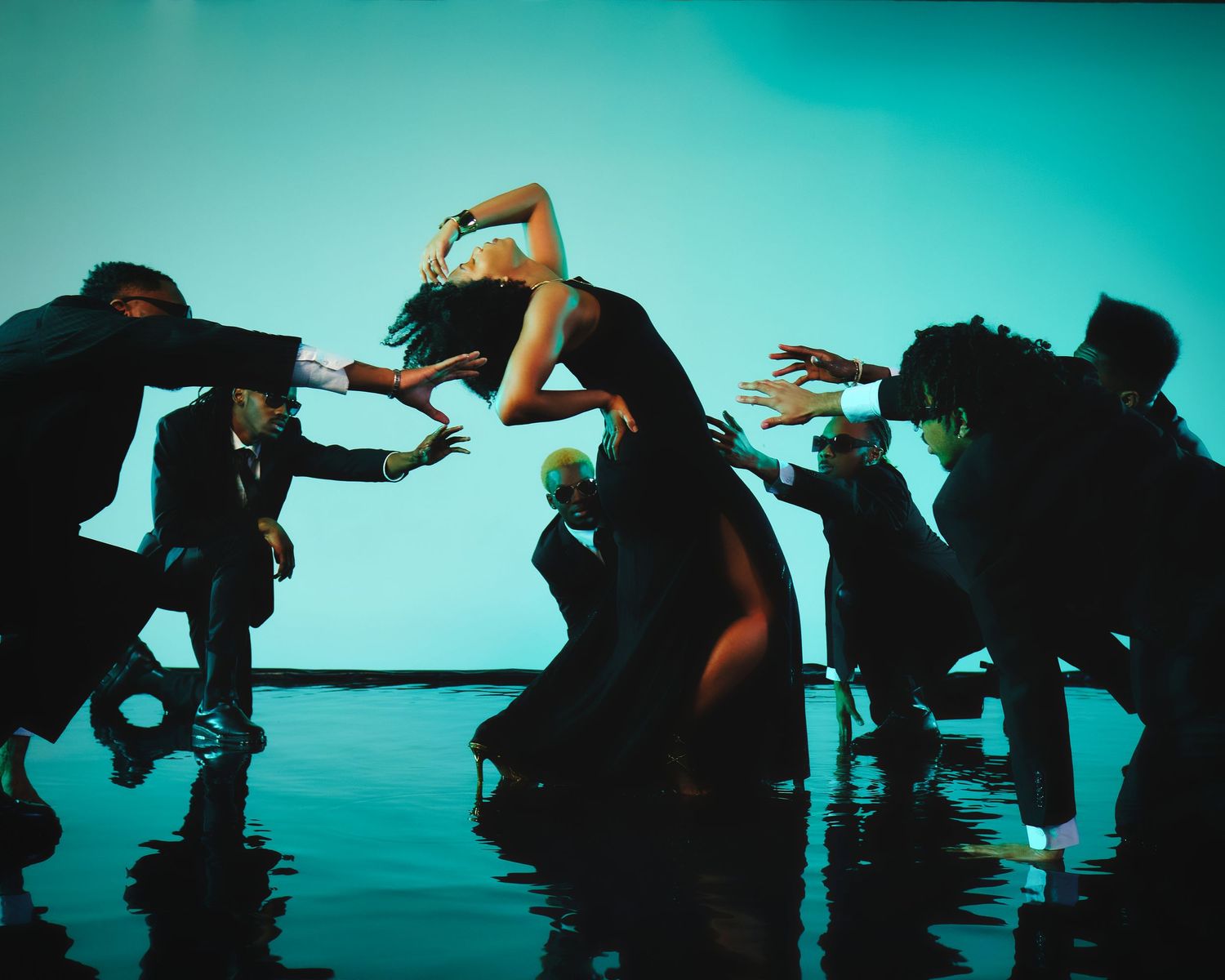 Silhouetted dancers performing against blue backdrop with dramatic lighting.