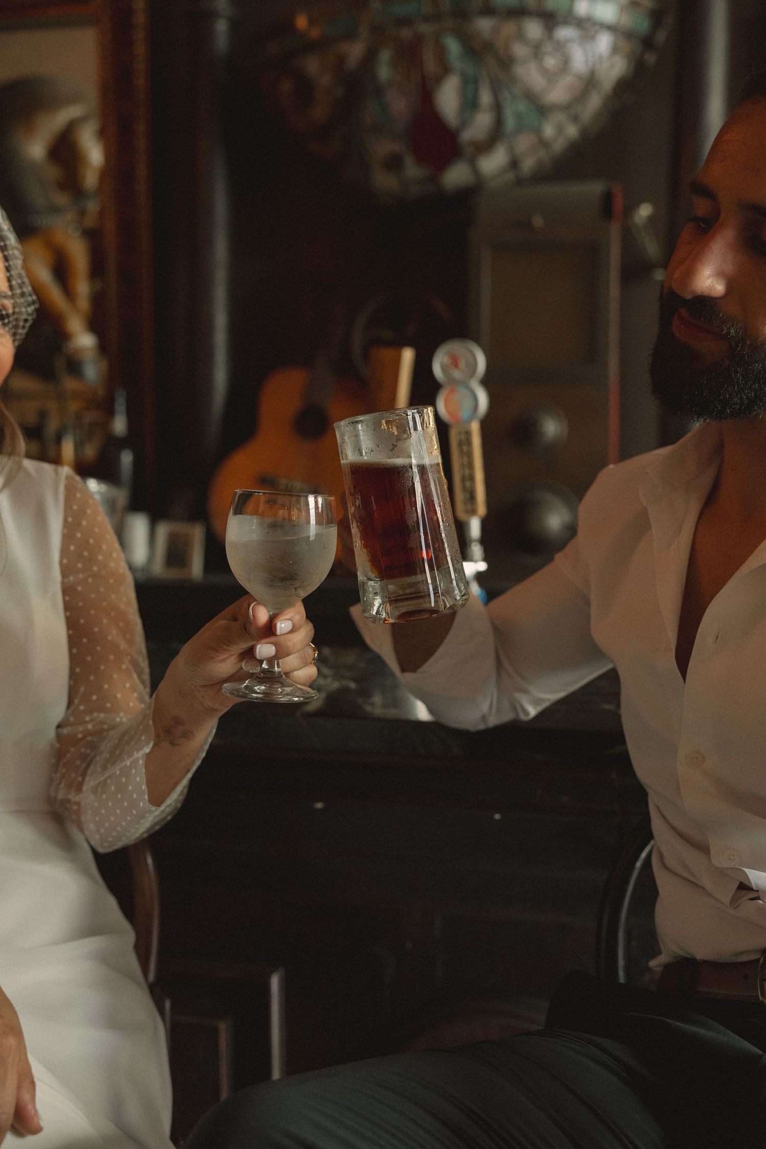 Couple in formal attire toasting with wine glasses in an intimate restaurant setting.