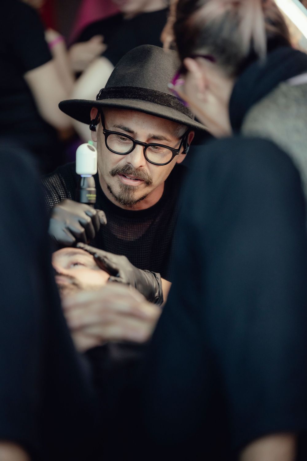 A man in glasses and fedora concentrates during an artistic session.