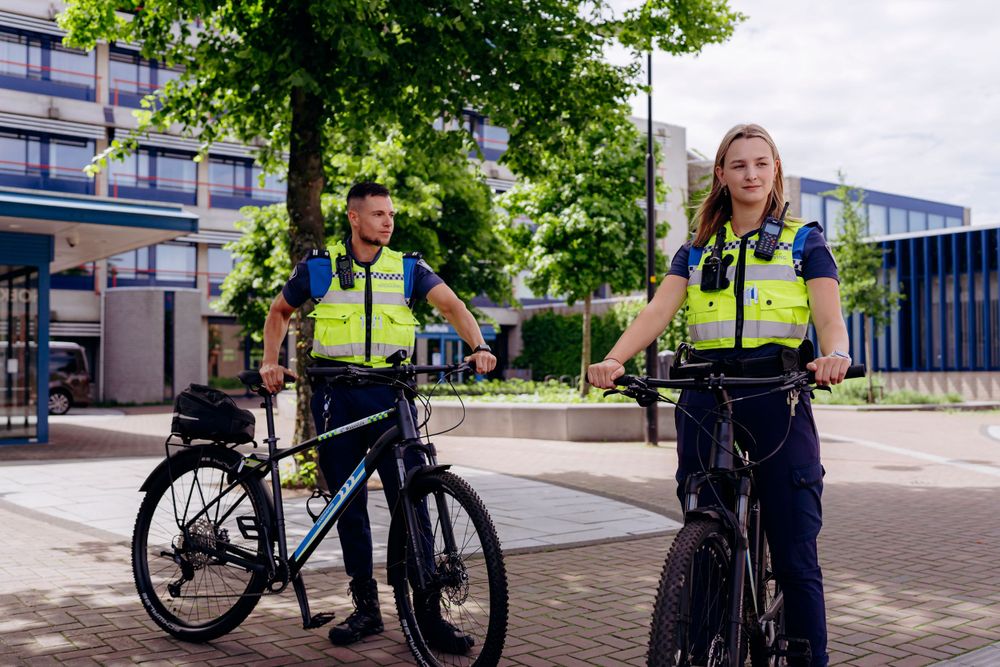 Police officers standing with their bicycles on a city street.