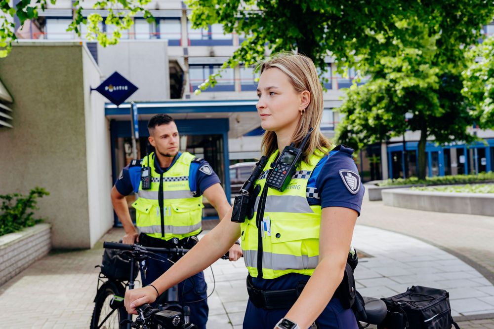 Police officers on bicycles patrolling an urban area on a sunny day.