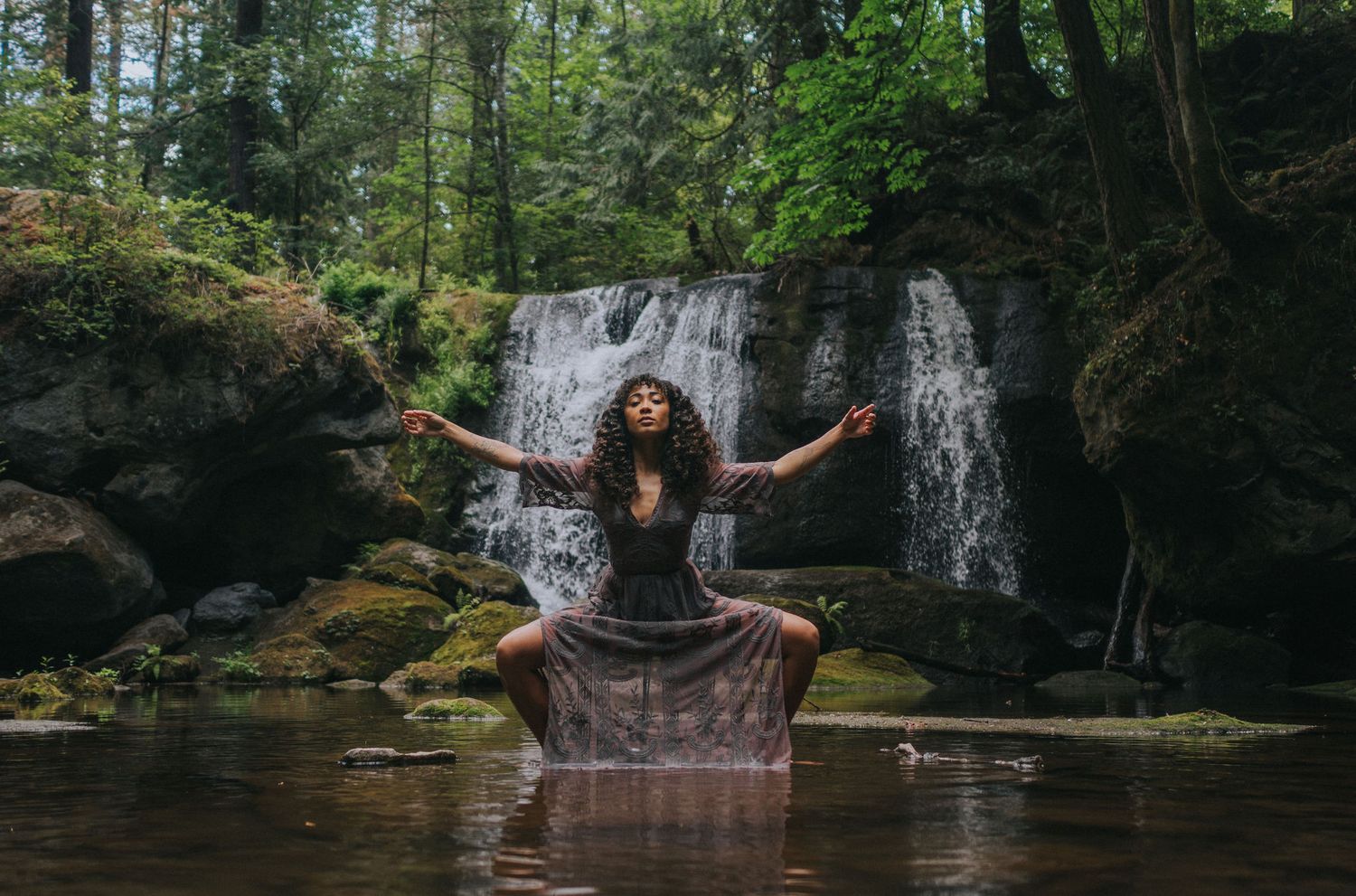 Woman in a powerful stance in front of a waterfall