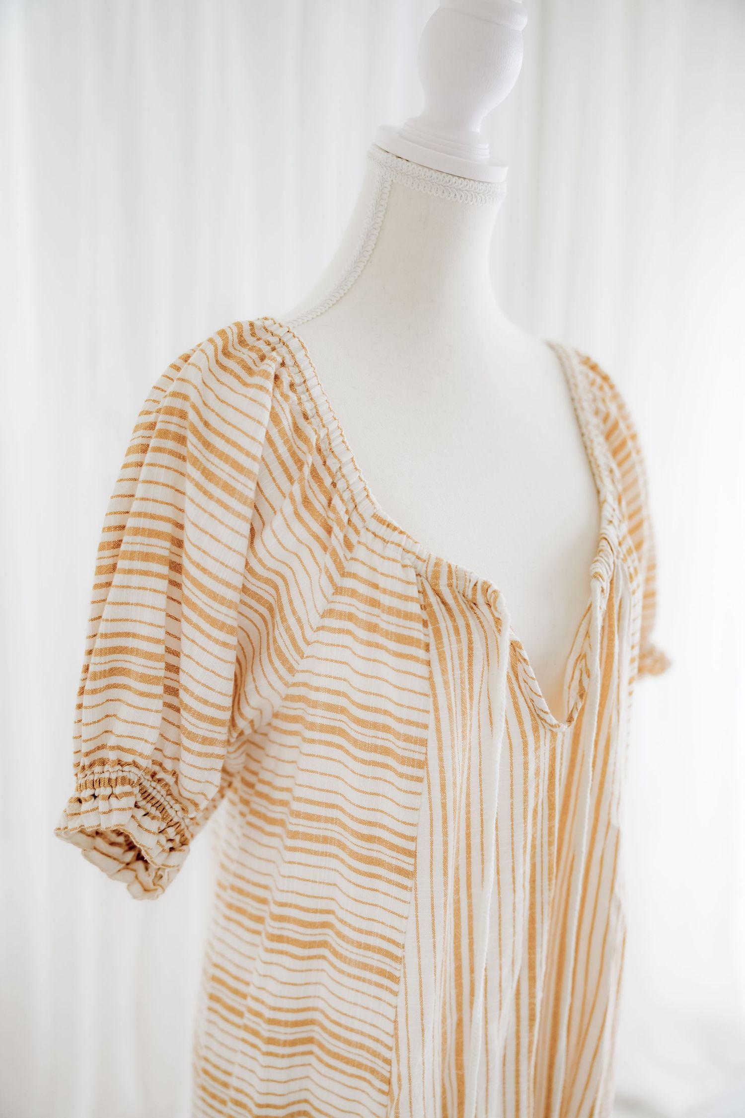 Close-up of puff sleeve detail on beige striped cotton dress.