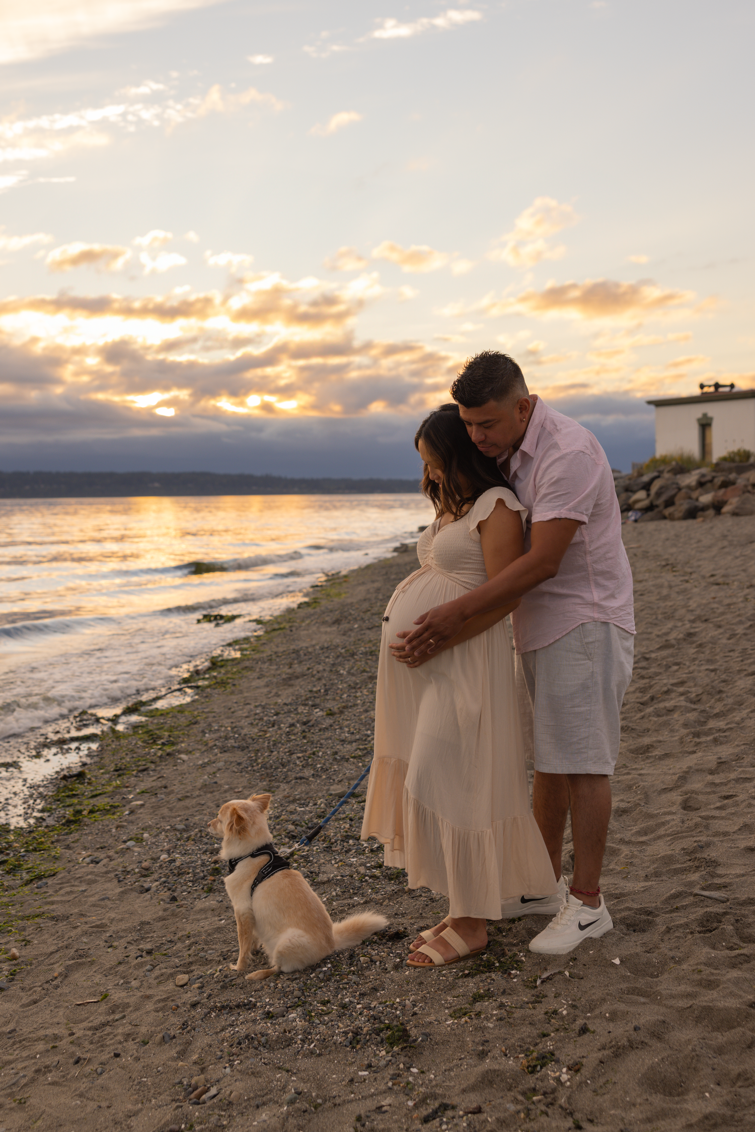 A romantic sunset beach scene with a couple and their dog enjoying the golden hour by the water.