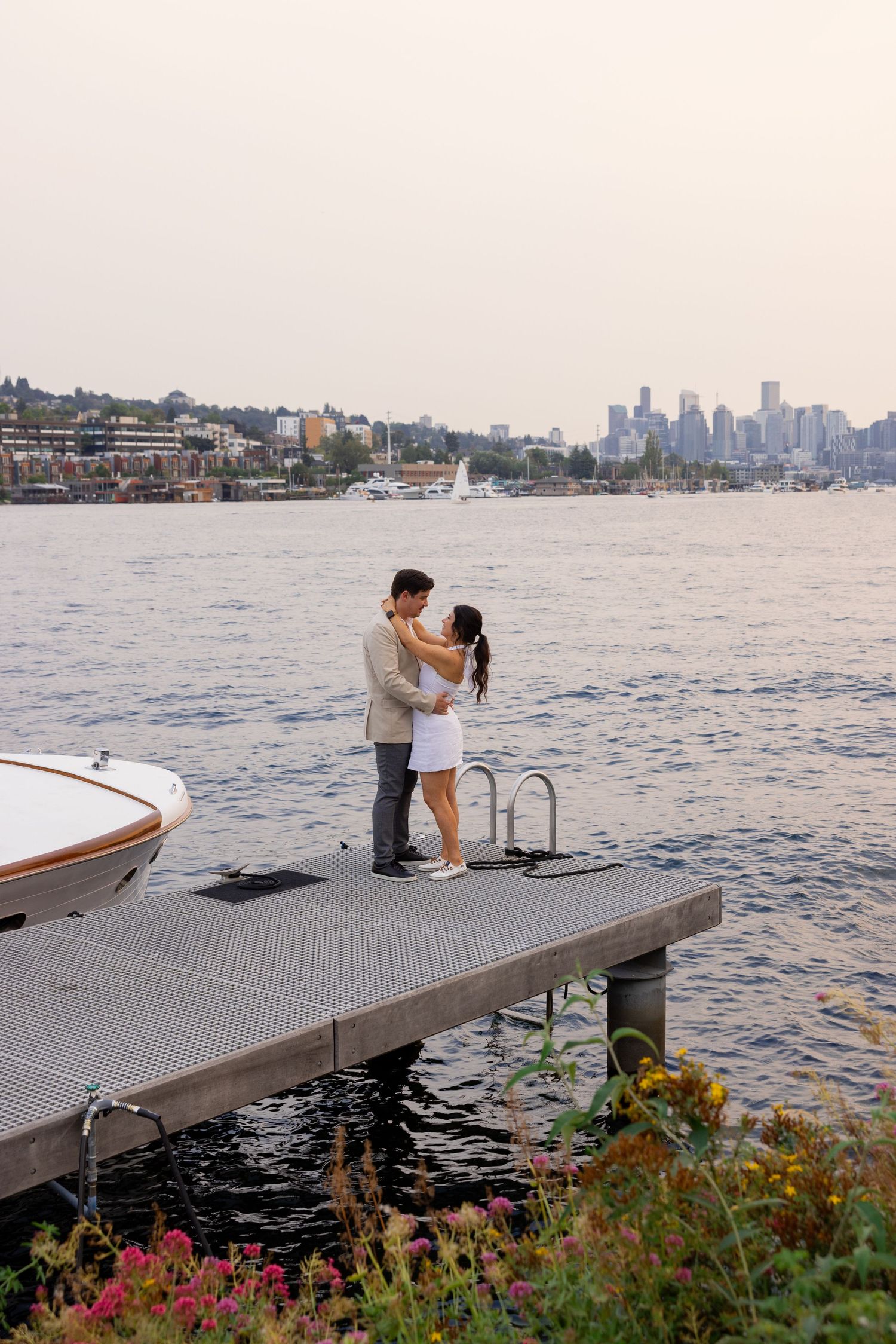A romantic moment on a dock overlooking the city skyline at sunset.