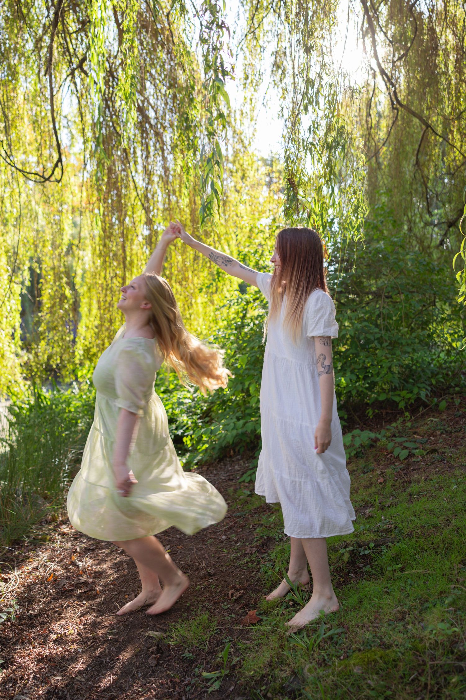 Playful dancing scene beneath willow branches with flowing dresses and dappled sunlight.