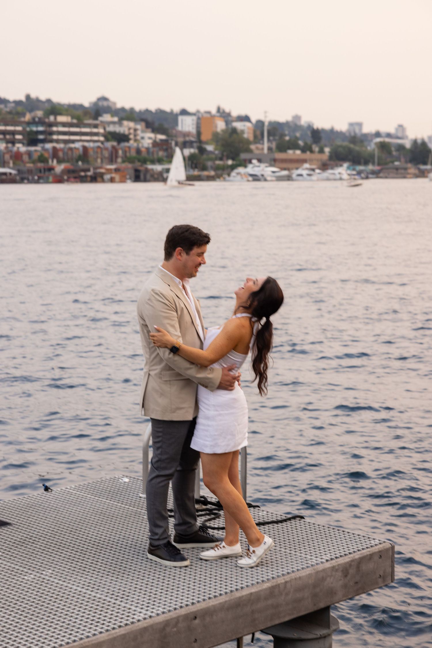 A tender moment shared on a floating dock with boats and waterfront views.