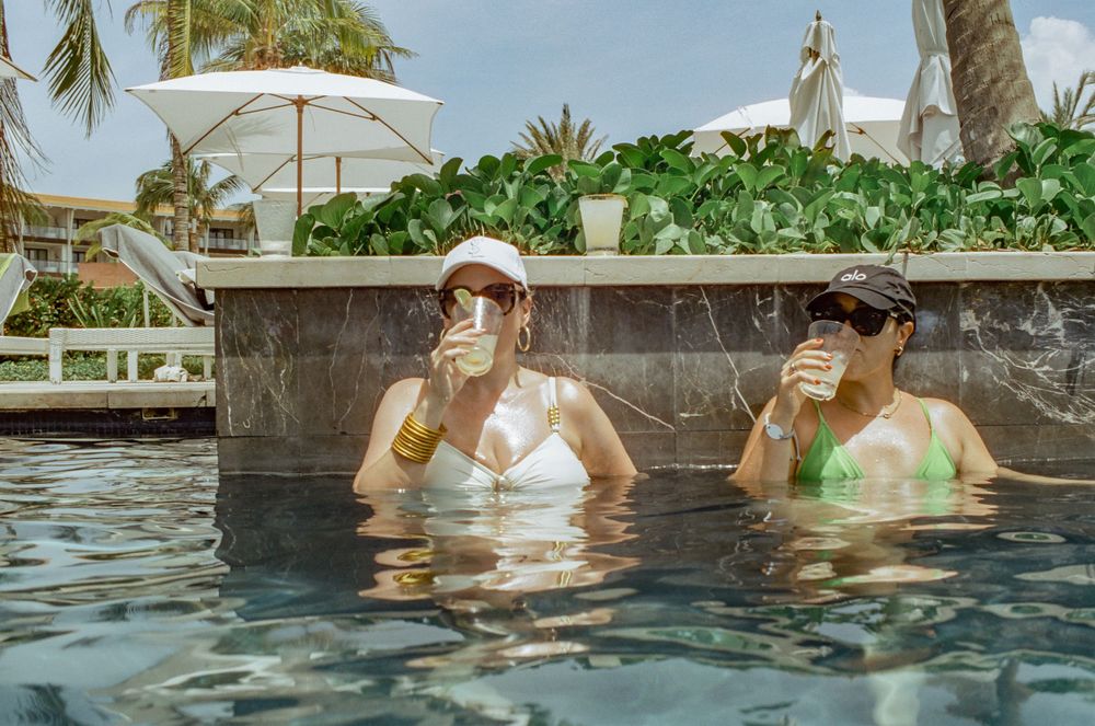 Two people enjoying a refreshing soak in a resort pool surrounded by palm trees.