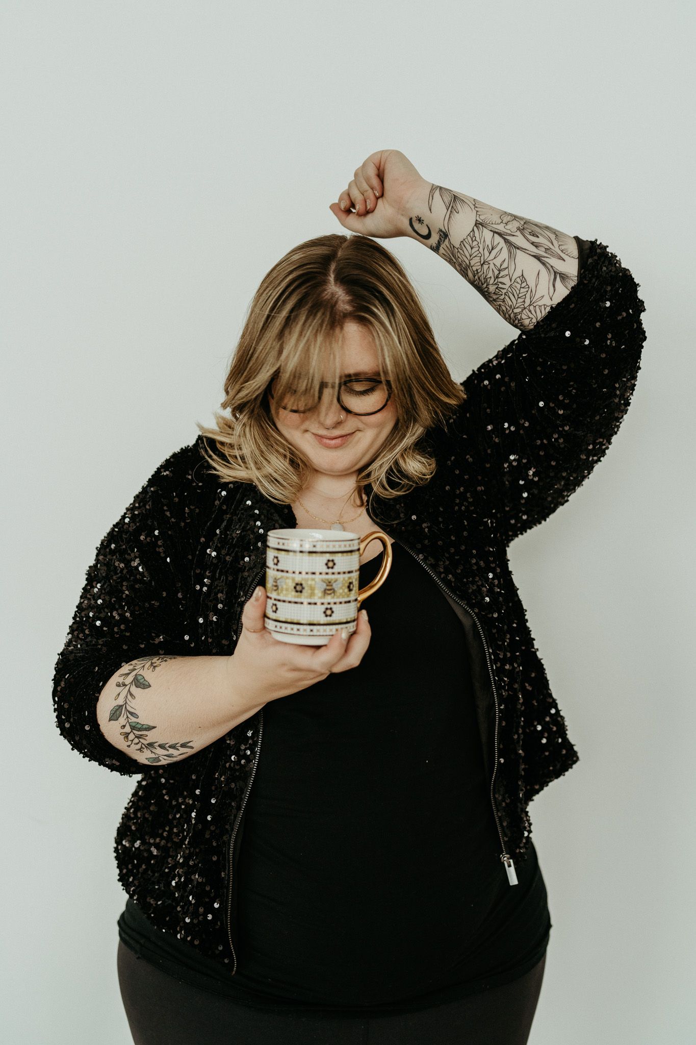 Cozy winter vibes with sparkly black cardigan and coffee mug against neutral background.