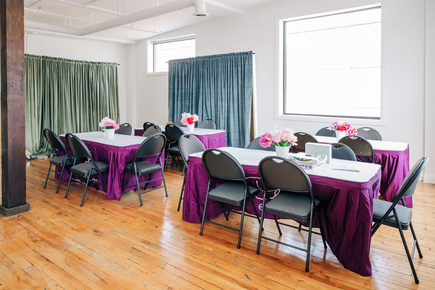 Banquet setup with purple tablecloths and folding chairs in bright room.