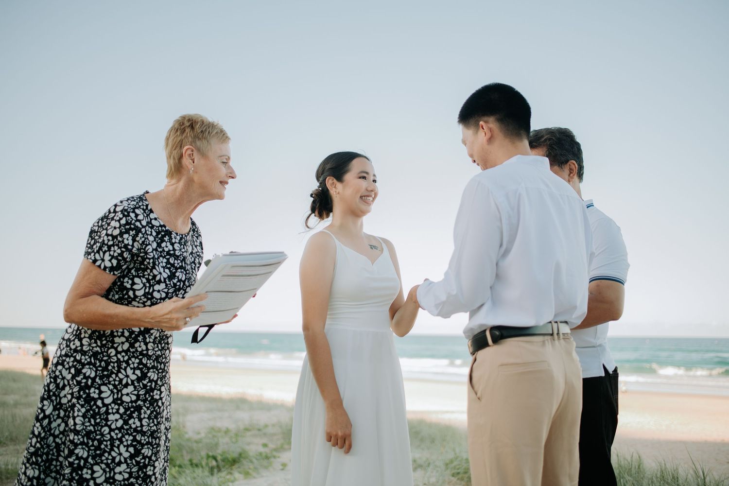 A beachside wedding ceremony with a couple exchanging vows by the ocean.