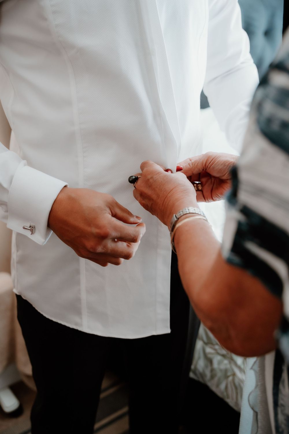 Close-up shot of hands adjusting cufflinks on a white dress shirt sleeve.