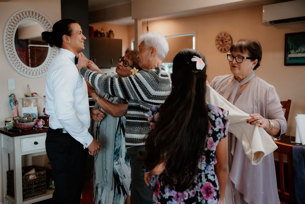 Multiple people help with wedding preparations in a warmly lit room.