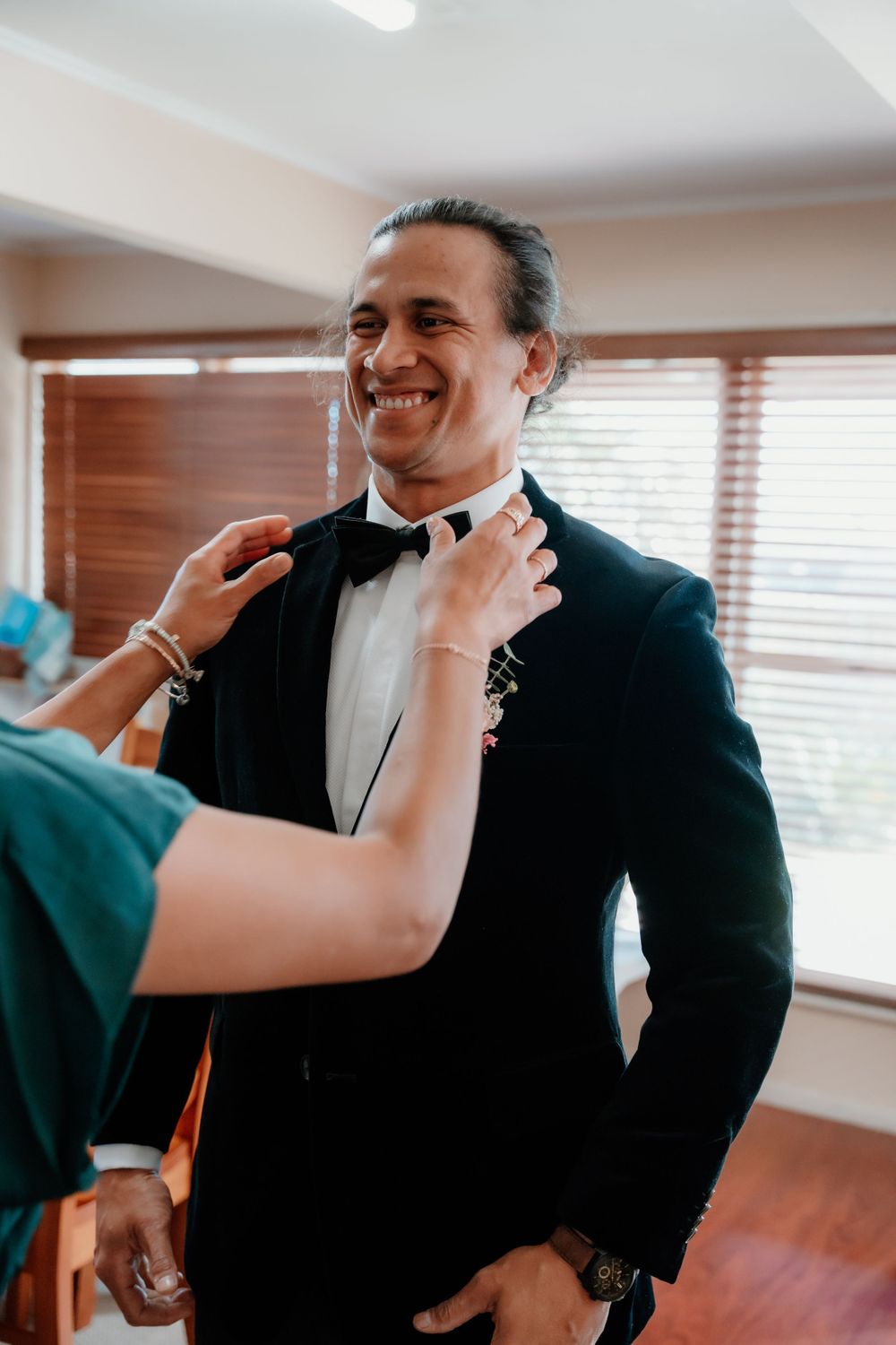A pre-wedding moment showing final adjustments being made to the groom's bow tie.