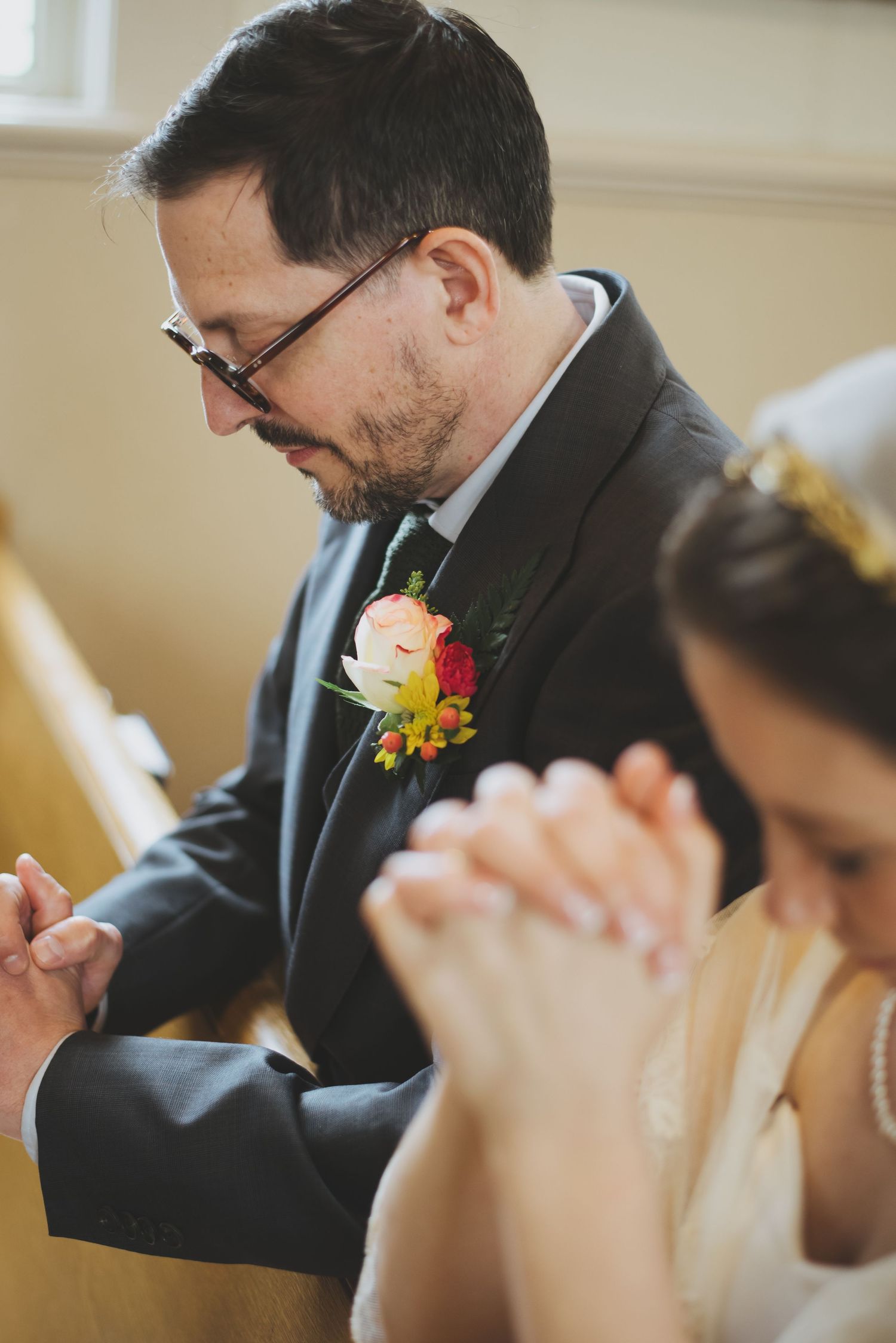 A solemn moment during a wedding ceremony as bride and groom bow their heads in prayer.