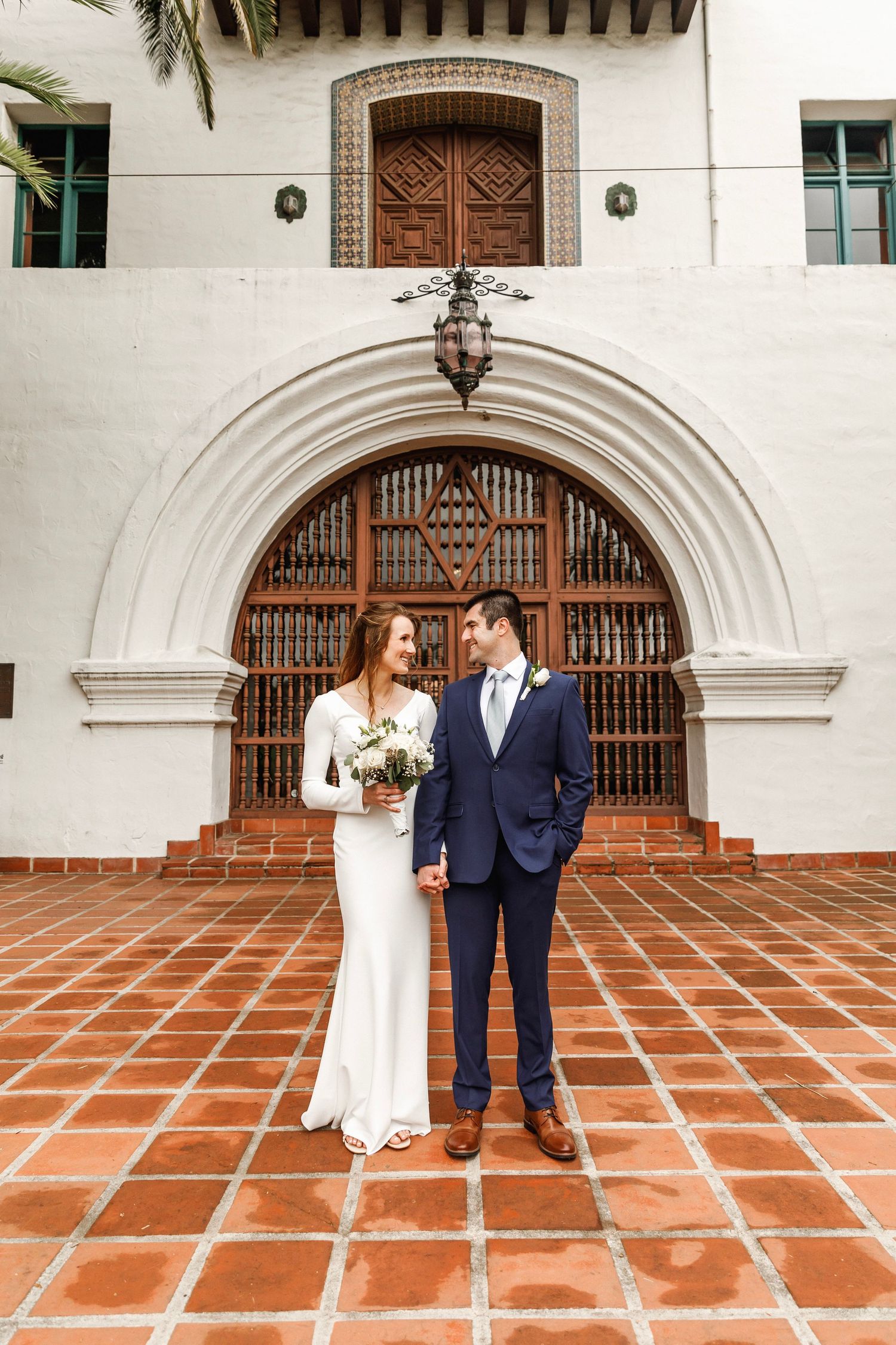 Bride and groom standing together in front of an ornate Spanish Colonial arch at Santa Barbara Courthouse.